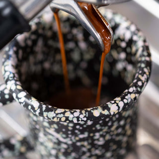Espresso coffee pouring into speckled mug